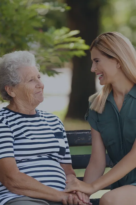 Friendly caregiver engaging in conversation with an elderly woman in a living room.